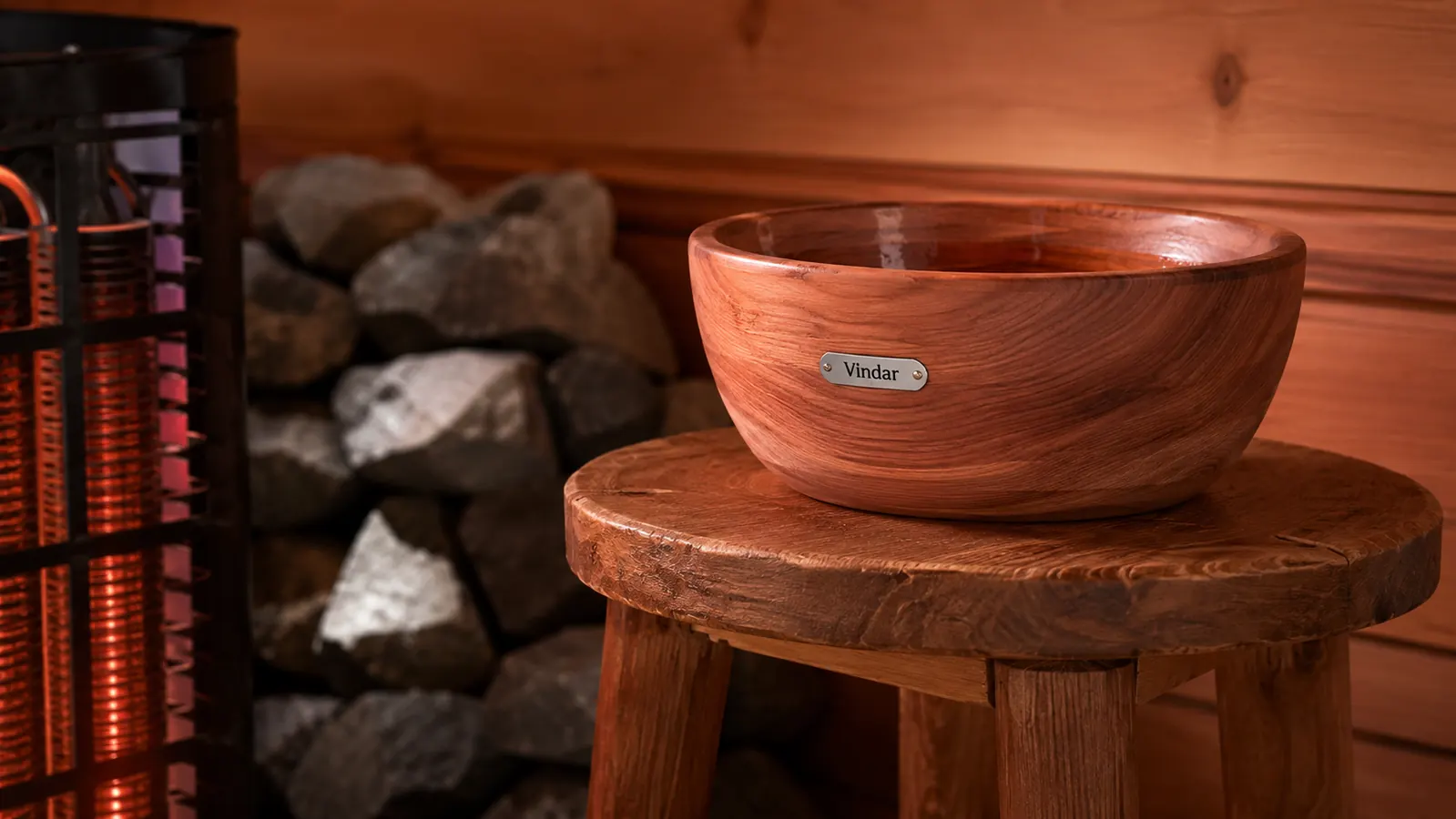 Vindar cedar bowl placed on a stool a safe distance from the glowing heater rocks inside a home sauna
